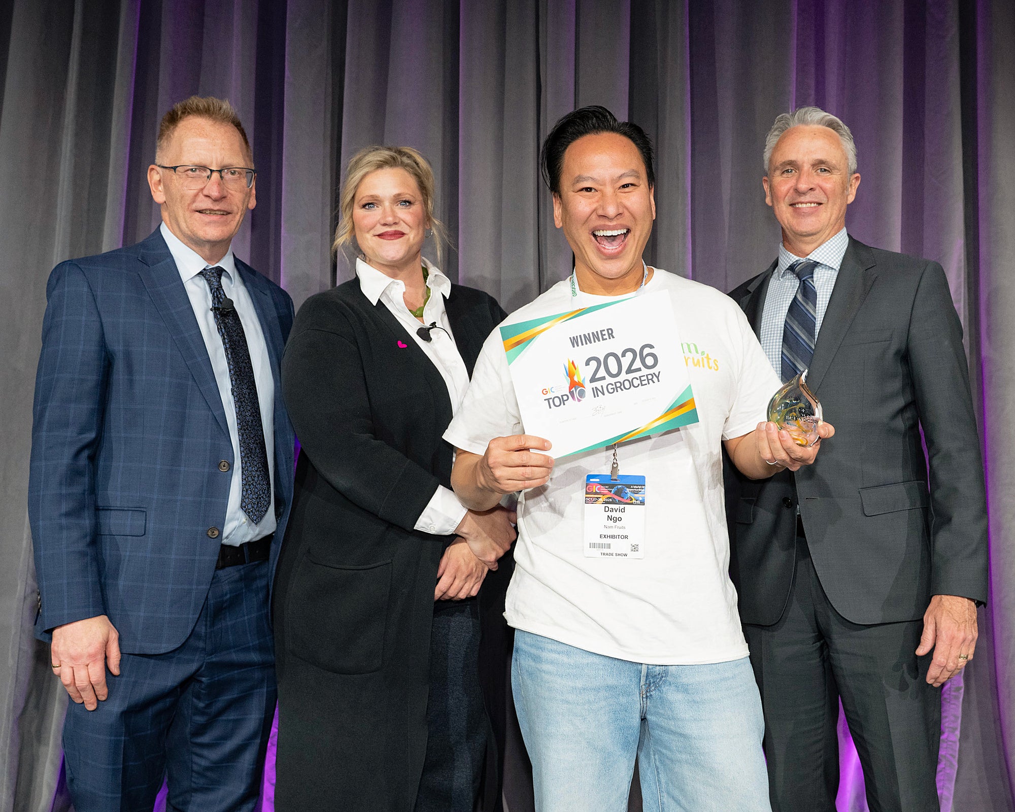David Ngo, founder of Nam Fruits, on stage at Grocery Innovations Canada 2026 with the Best Snack certificate and trophy, with the award presenters